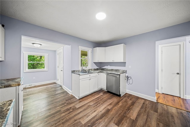 579 Main St, Conneaut, OH 44030 - kitchen with stainless steel dishwasher, plenty of natural light, dark wood-style flooring, and white cabinets
