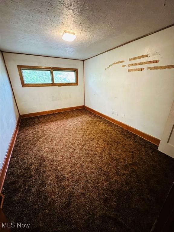 carpeted empty room with a textured ceiling and baseboards
