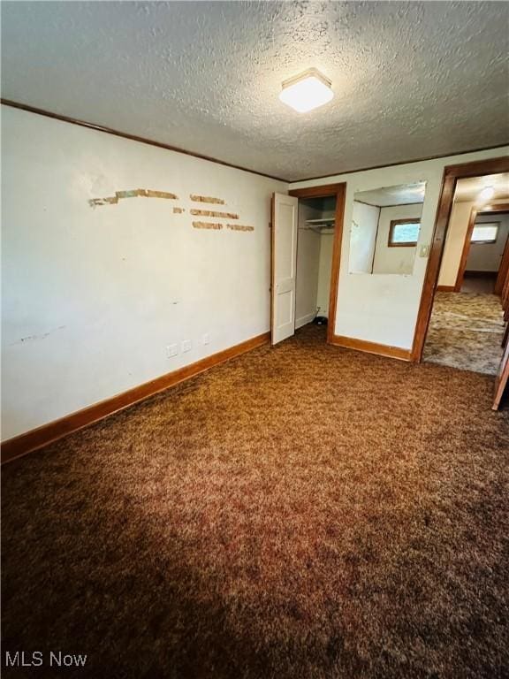 unfurnished bedroom featuring dark carpet, a textured ceiling, a closet, and baseboards