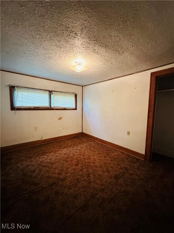 empty room featuring carpet floors, a textured ceiling, and baseboards