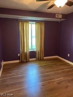 unfurnished room featuring a ceiling fan, baseboards, and wood finished floors