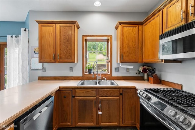 kitchen with stainless steel appliances, a sink, light countertops, brown cabinets, and recessed lighting