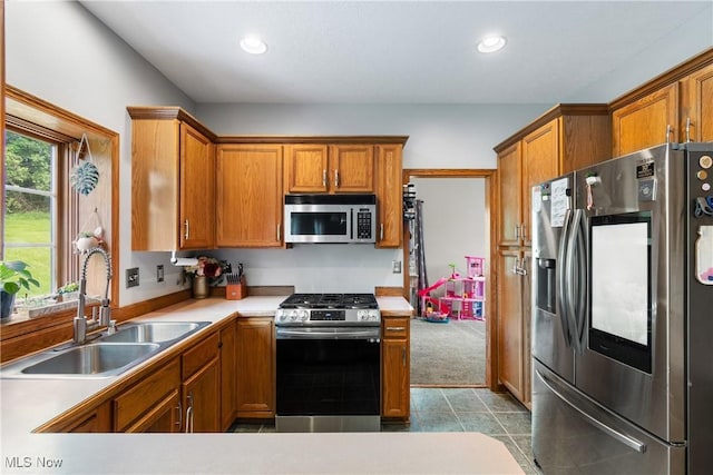 kitchen with stainless steel appliances, a sink, brown cabinets, light countertops, and recessed lighting