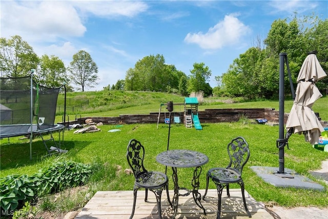 view of home's community with a trampoline, a playground, and a lawn