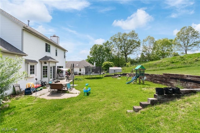 view of grassy yard featuring a trampoline, a playground, and a patio