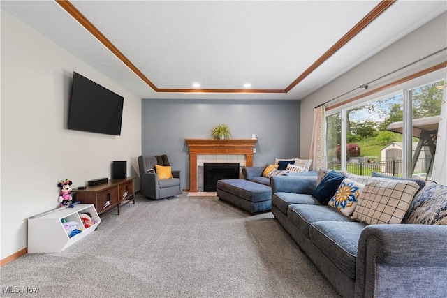 living room featuring carpet floors, a tray ceiling, a tiled fireplace, and recessed lighting