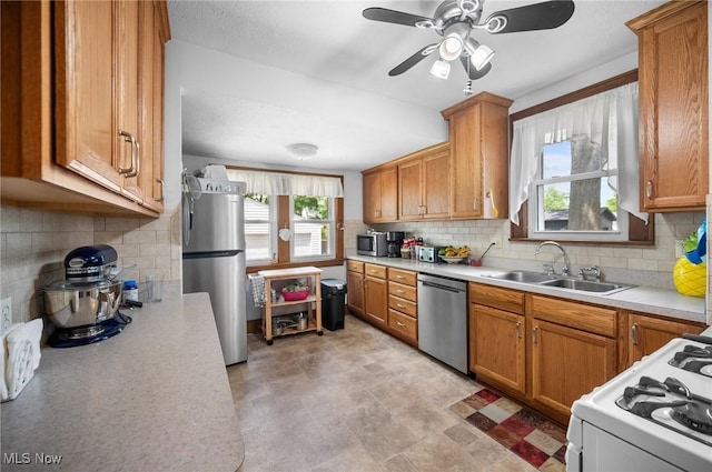 kitchen featuring appliances with stainless steel finishes, a sink, light countertops, and decorative backsplash