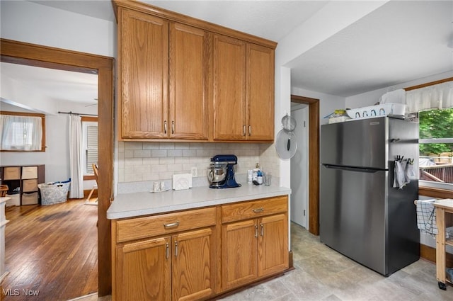 kitchen with freestanding refrigerator, light countertops, tasteful backsplash, and brown cabinetry