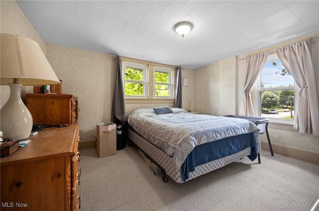 bedroom with light colored carpet and baseboards