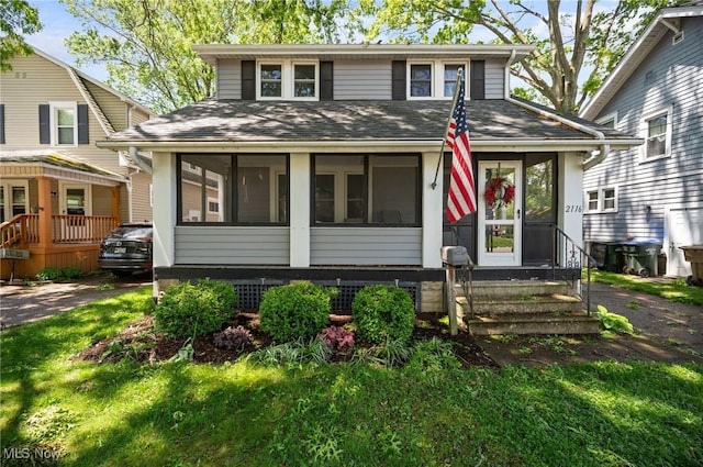 view of front of home with a sunroom, a shingled roof, and entry steps
