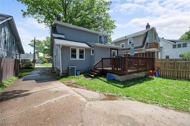 back of house featuring cooling unit, a wooden deck, and a chimney