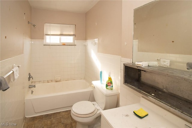bathroom with toilet, a wainscoted wall, tile walls, tub / shower combination, and vanity