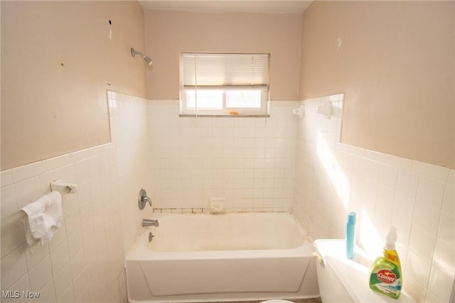 bathroom featuring tile walls, a wainscoted wall, and bathtub / shower combination