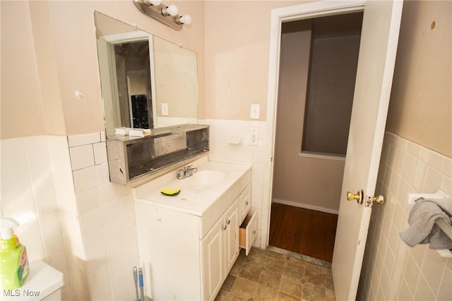 bathroom featuring tile walls, wainscoting, and vanity