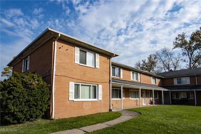 rear view of house featuring brick siding and a yard