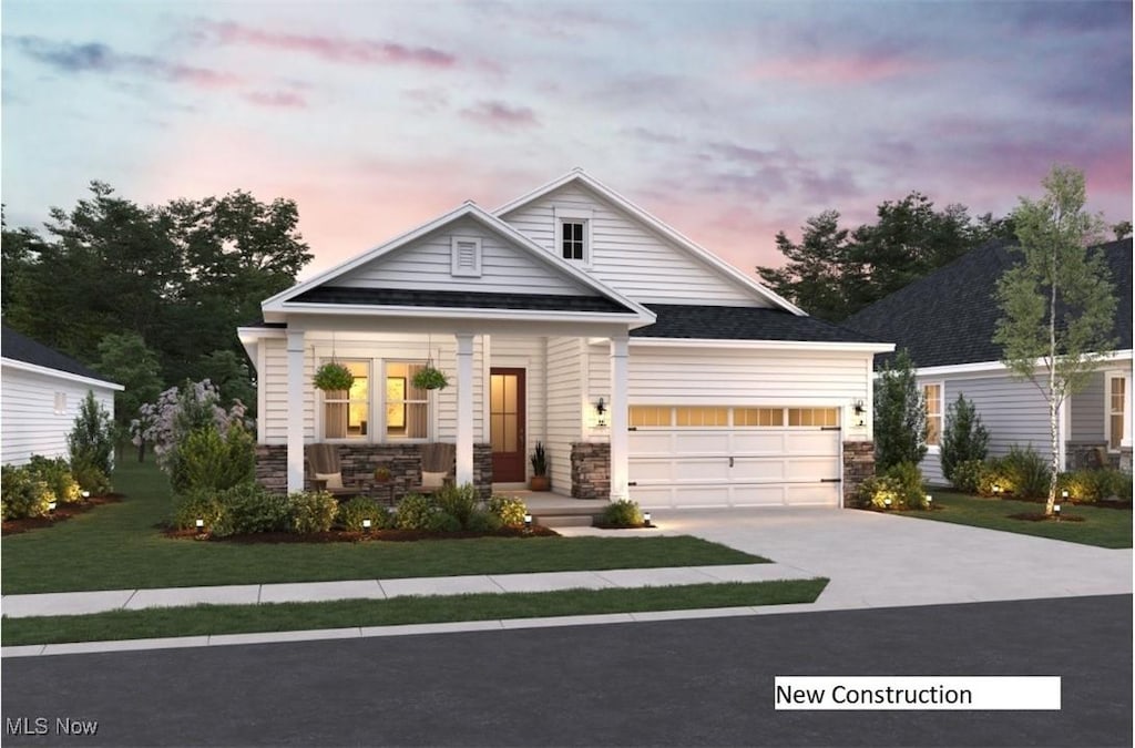 2172 Myla Way, Amherst, OH 44001 - view of front facade with covered porch, stone siding, concrete driveway, a lawn, and an attached garage