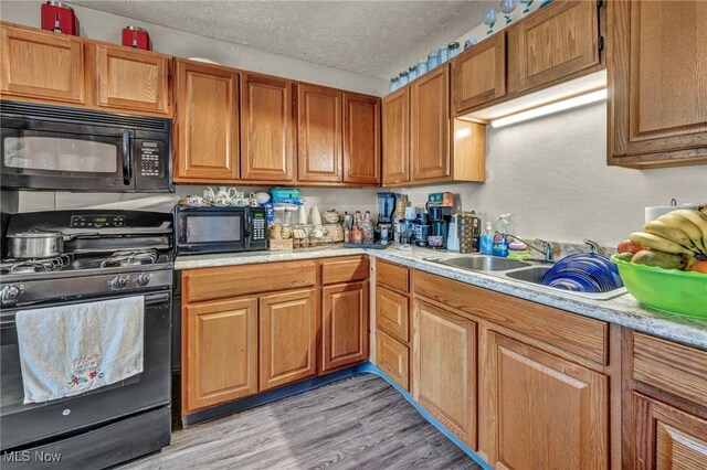 2212 Randall St, Lorain, OH 44052 - kitchen featuring black appliances, light countertops, a textured ceiling, light wood-style floors, and brown cabinets