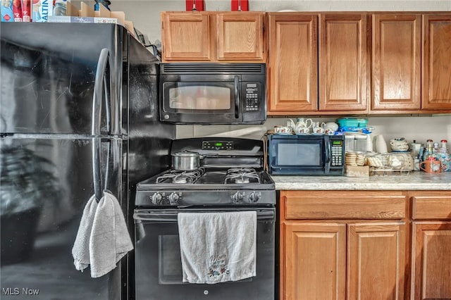 2212 Randall St, Lorain, OH 44052 - kitchen featuring black appliances, light countertops, and brown cabinetry