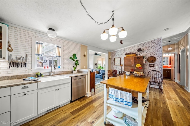 7214 Ridge Ave, Conneaut, OH 44030 - kitchen featuring dishwasher, wallpapered walls, a sink, light wood-style flooring, and white cabinetry