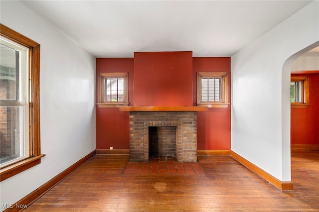 494 W Columbia St, Alliance, OH 44601 - unfurnished living room with wood-type flooring, a fireplace, arched walkways, and baseboards