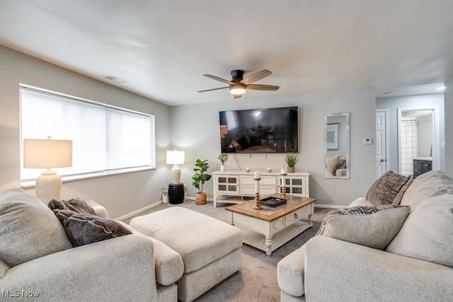 living area with baseboards, carpet floors, and ceiling fan