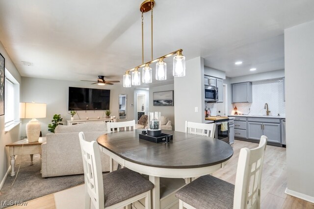 dining space with a ceiling fan, light wood-style flooring, and baseboards