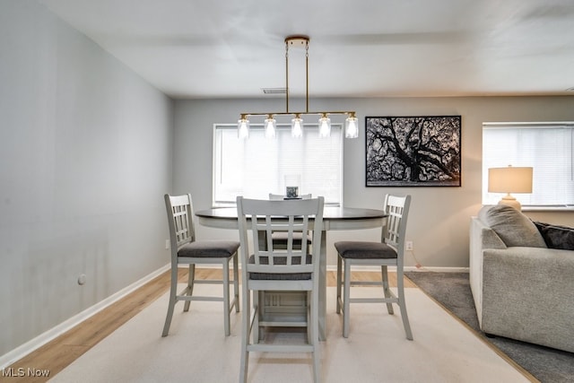 dining room with healthy amount of natural light, baseboards, and light wood-style flooring