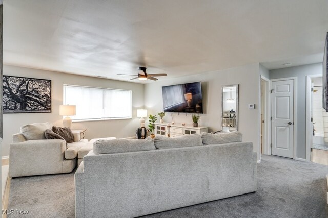 carpeted living room with ceiling fan and baseboards