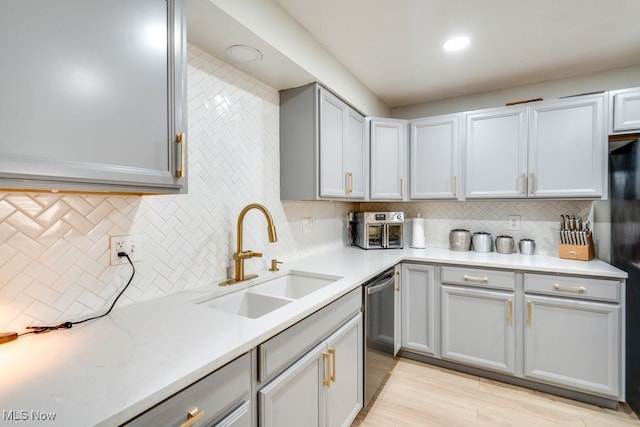 kitchen with a sink, dishwasher, decorative backsplash, recessed lighting, and light wood-style flooring
