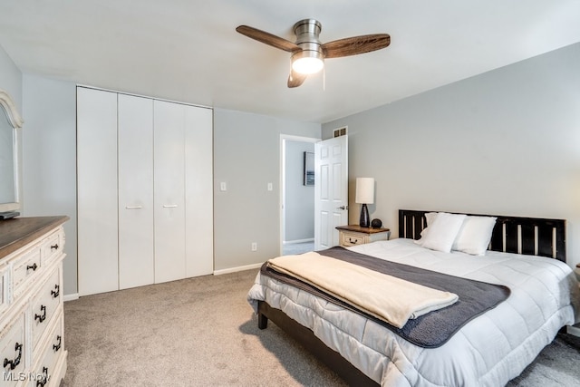 bedroom with light colored carpet, a closet, a ceiling fan, and baseboards