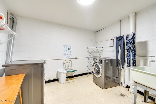 laundry area featuring separate washer and dryer, tile patterned floors, and concrete block wall