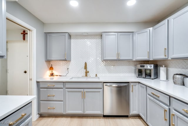 kitchen with dishwasher, a sink, light countertops, and recessed lighting