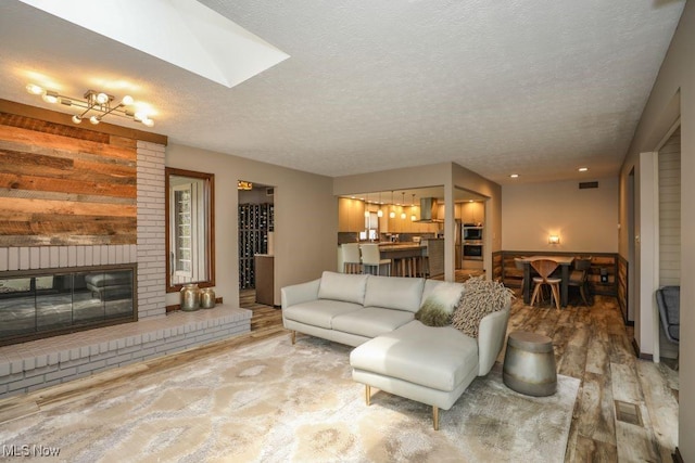 1367 Mockingbird Dr, Kent, OH 44240 - living area with wood finished floors, a textured ceiling, a brick fireplace, and a skylight
