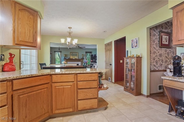 3277 Plainview Rd, Ravenna, OH 44266 - kitchen with a chandelier, light stone countertops, a textured ceiling, brown cabinets, and hanging light fixtures