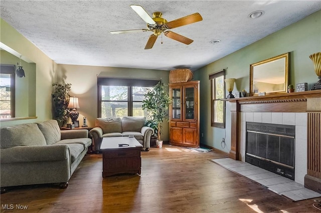3277 Plainview Rd, Ravenna, OH 44266 - living room with plenty of natural light, wood-type flooring, a tiled fireplace, ceiling fan, and a textured ceiling