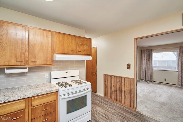 1658 Bronson Rd, Akron, OH 44305 - kitchen featuring white range with gas cooktop, under cabinet range hood, light countertops, decorative backsplash, and light wood-type flooring