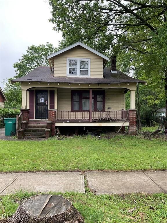 17205 Mapleboro Ave, Maple Heights, OH 44137 - bungalow-style home with covered porch, a chimney, a front lawn, and brick siding