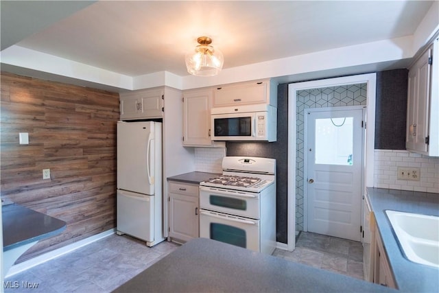 338 Applegrove St NE, North Canton, OH 44720 - kitchen with white appliances, wooden walls, a sink, decorative backsplash, and baseboards