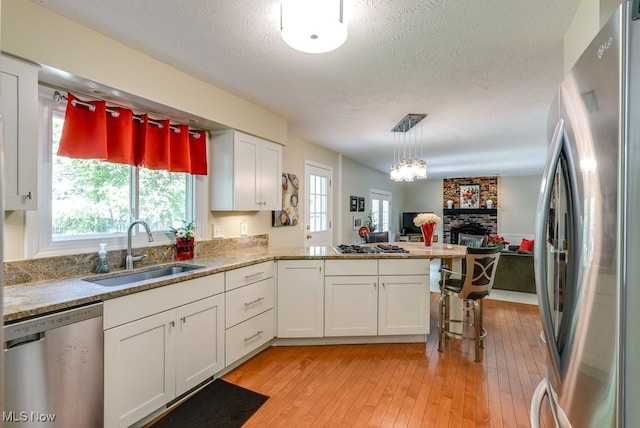 139 Elm Ct, Chagrin Falls, OH 44022 - kitchen with stainless steel appliances, a sink, open floor plan, white cabinetry, and a peninsula