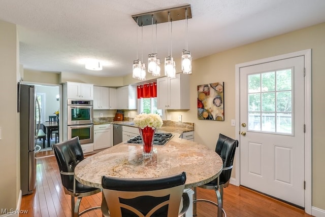 139 Elm Ct, Chagrin Falls, OH 44022 - dining area with light wood-style flooring, a textured ceiling, and baseboards