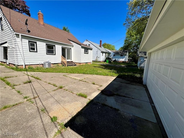 24421 Effingham Blvd, Euclid, OH 44117 - back of house featuring entry steps, roof with shingles, a chimney, cooling unit, and a garage