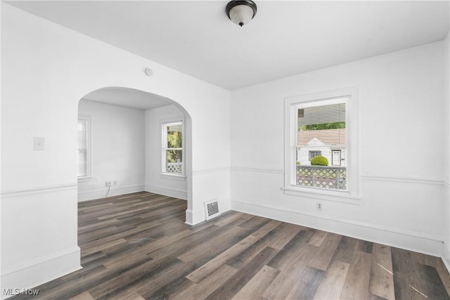 1210 17th St NE, Canton, OH 44705 - unfurnished room with arched walkways, dark wood-type flooring, healthy amount of natural light, and baseboards