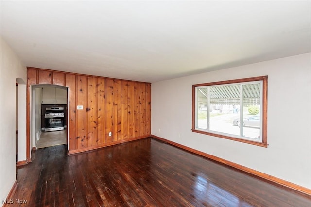 125 E 30th St, Lorain, OH 44055 - spare room featuring arched walkways, dark wood-type flooring, and baseboards