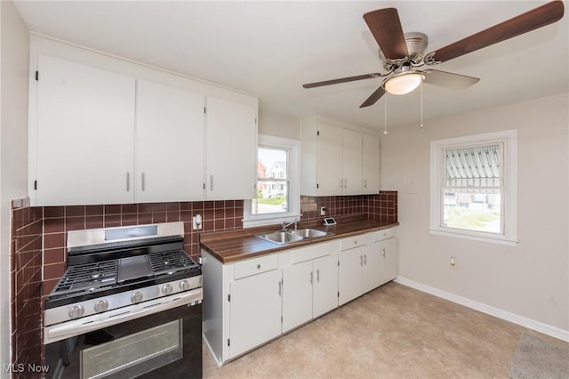 125 E 30th St, Lorain, OH 44055 - kitchen featuring stainless steel gas range, a sink, decorative backsplash, white cabinets, and baseboards