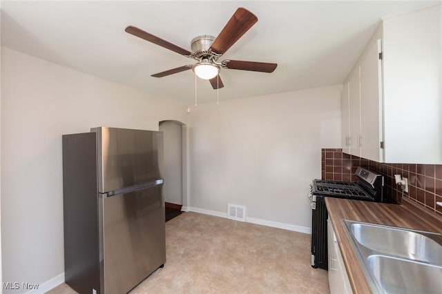 125 E 30th St, Lorain, OH 44055 - kitchen with stainless steel appliances, white cabinets, tasteful backsplash, a sink, and arched walkways