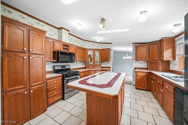 10597 State Route 82, Windham, OH 44288 - kitchen featuring stainless steel gas range, black microwave, wallpapered walls, tile counters, and a sink