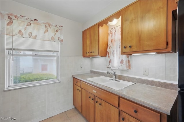 21031 Ball Ave, Euclid, OH 44123 - kitchen featuring a sink, brown cabinetry, light tile patterned floors, light countertops, and tile walls