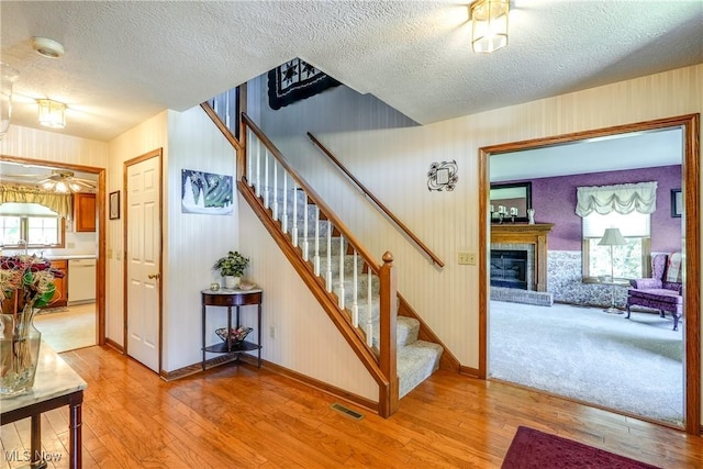 961 Prescot Ave NW, Massillon, OH 44646 - stairway featuring wood finished floors, a textured ceiling, a brick fireplace, plenty of natural light, and baseboards