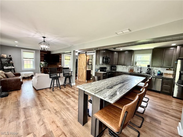 7509 S Palmyra Rd, Canfield, OH 44406 - kitchen featuring a barn door, appliances with stainless steel finishes, healthy amount of natural light, a kitchen bar, and recessed lighting