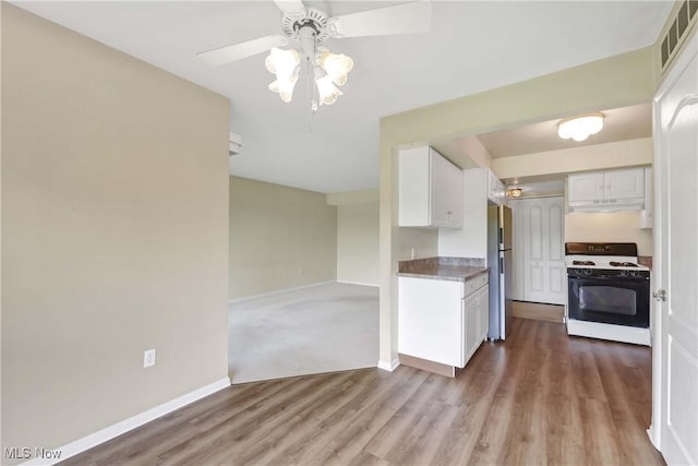 1145 Canyon View Rd Unit 206, Sagamore Hills, OH 44067 - kitchen with range with gas stovetop, freestanding refrigerator, white cabinets, under cabinet range hood, and a ceiling fan